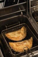 Delicious golden empanadas frying in hot oil in a busy kitchen at lunchtime during a culinary event photo