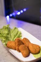 Crispy golden nuggets served on fresh lettuce with soft ambient lighting in the background captures the delicious essence of comfort food at a casual dining setting photo