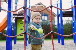 un adorable niñito alegremente jugando a un al aire libre patio de recreo rodeado por un vistoso alpinismo estructura y un divertido deslizar, creando un vibrante atmósfera y Fomentando contento infancia recuerdos foto