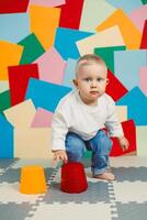 An adorable, energetic toddler is actively playing with an assortment of colorful cups set against a vibrant and fun background, showcasing the joys of childhood exploration and creativity photo