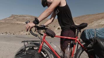 young male fit cyclist on a touring bike pauses to check their phone for navigation while surrounded by rugged mountain scenery, combining adventure with digital guidance video