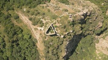 Aerial Armazi Fortress ruins on steep ridge with tilted rock formations and forested hills, part of important ancient defense system near Mtskheta, Georgia video