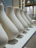 Row of white vases are lined up on a shelf photo