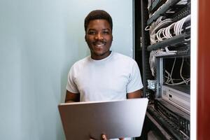 Young technician working in server room, managing cables and technology efficiently while smiling photo
