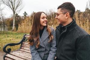 Couple enjoying a cozy moment on a park bench during an overcast autumn day by the lake photo