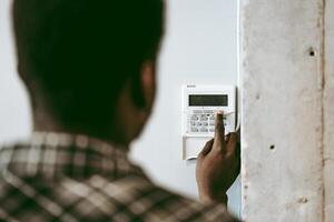 Man setting security system at home in the afternoon, focusing on keypad and monitoring device for safety photo