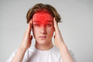 Young man experiencing headache in a minimal background setting while holding his forehead in discomfort photo