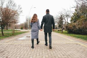 Couple walking hand in hand through a park on a cloudy day in autumn photo