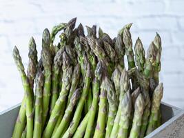 Close up of green asparagus neatly arranged in a weathered gray crate, ideal for market or farm visuals photo