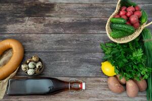 A hearty flatlay of okroshka components, complete with kvass, displayed on a deep wooden background. photo