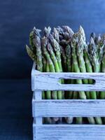 Harvested green asparagus neatly arranged in a weathered gray crate, ideal for market or farm visuals photo