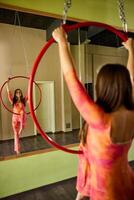 Woman Doing Acrobatics On Aerial Hoop in front of mirror. photo