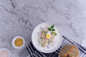 Flatlay of ready to serve tasty okroshka with bread and mustard photo