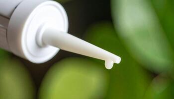 Close-up View of an Applicator Tip Dispensing a Cream Against a Blurred Green Background in a Serene Setting photo
