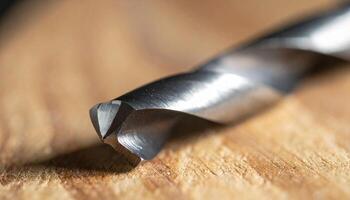 Close-up View of a Metal Drill Bit Resting on Wooden Surface During Workshop Activity photo