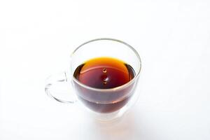 Coffee Background Close up of a Glass Cup with Dark Tea a Single Drop Falling into the Liquid photo