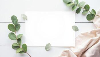 Blank paper with eucalyptus leaves on white table top view photo