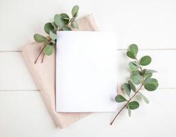 Blank notebook with eucalyptus leaves on white wooden background photo