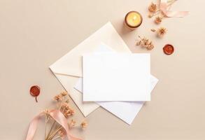 Blank white envelope with wax seal, dried flowers and candle on beige background photo