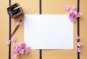 Top view of a blank paper and ink pen on a wooden table with cherry blossom flowers photo