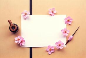 A blank paper with pink flowers and a pen on a wooden table top view photo