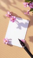 A blank sheet of paper with flowers and a brush on a wooden table photo