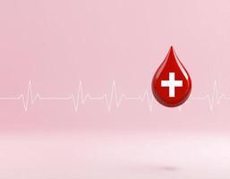 A red blood drop is floating in front of a heartbeat line photo