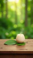 Candle on wooden table with green leaves in the background photo