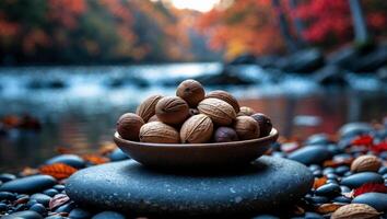 Walnuts in Bowl by Stream with Autumn Leaves on Stones photo