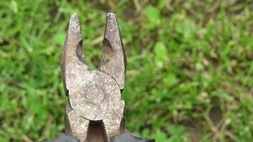Rusty pliers resting on grass with blades exposed in a natural outdoor setting during daylight photo