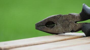 Close-up view of rusty pliers resting on a wooden surface in a garden setting during daylight photo