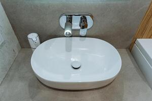 A white sink is placed in a bathroom, featuring a sleek faucet attached to it, making it both a functional plumbing fixture and an essential part of the bathrooms interior design photo