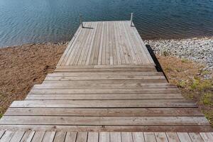 A beautifully crafted wooden dock that extends out towards a serene body of water, providing a scenic pathway for visitors to enjoy the natural surroundings and take in the calming views photo