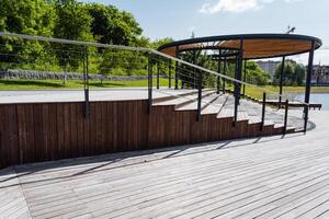 A wellconstructed wooden deck featuring stairs, along with a sturdy railing, is situated in a beautiful park, providing a cozy spot for visitors to relax and enjoy the natural surroundings photo