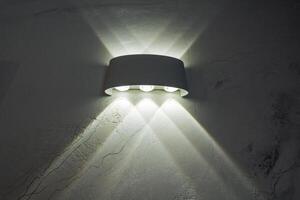 A bright and stylish white wall light is beautifully shining on a contrasting dark wall, creating an interesting play of shadows and illumination that enhances the ambiance of the room photo