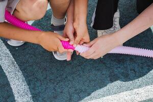 A lively group of energetic children are happily playing together with an engaging and fun pink toy that effectively captures their interest and sparks their creative imagination in delightful ways photo