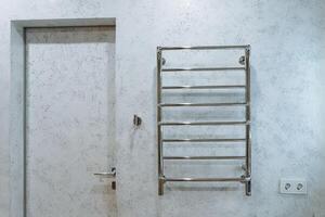 A towel rack is securely hanging on the wall right next to an entrance door, providing easy access for towels in a convenient location for individuals entering or exiting the room photo