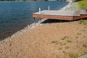 A beautiful wooden dock is perfectly located on the calm shore of a peaceful lake, offering a great place for relaxation and enjoying the tranquility of the water, surrounded by nature photo