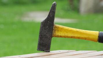 Hammer rests on wooden table with green grass in background during a sunny day photo