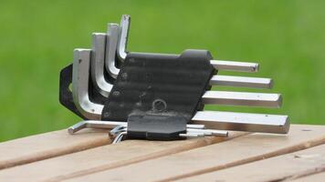 Various metal hex keys resting on a wooden table in a garden setting during daylight hours photo