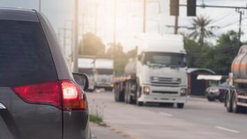 Traffic jam with several vehicles lined up on a road. Close up car with its tail lights illuminated. Traffic congestion during rush hour. Large truck drives past from the opposite side. photo