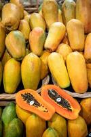 Halved fresh papaya with black seeds and price tag fills foreground at market stall. Full frame photo