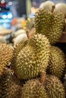 Durian fruits on supermarket shelf ready for customer selection, close up. Grocery stalls in Asia photo