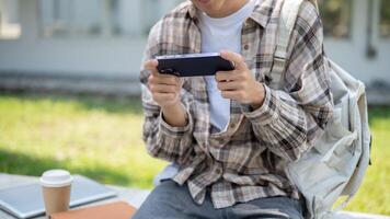 Close up of a man looking at phone holding with both hands while sitting on concrete bench in park. photo