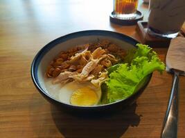 Chicken Rice Porridge with Egg and Lettuce in Blue Bowl photo