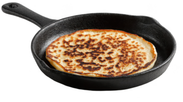 Deliciously browned pancake cooking in cast iron skillet on transparent background png