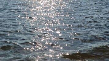 Bright sunlight generating glittering, sparkling reflections dancing across gently rippling water surface. video