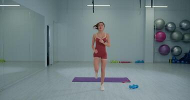 Girl athlete practicing butt kicks in a gym during a fitness session focusing on warm up exercises and agility training video