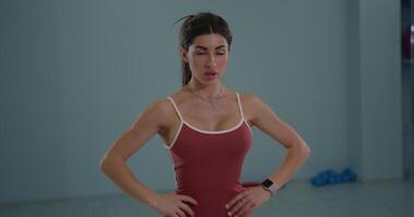 Girl athlete performs standing oblique twists in fitness studio while focusing on core strength and balance during workout session video