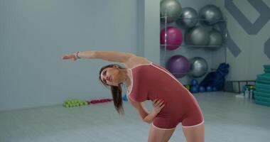 Girl athlete performing dynamic stretches in fitness studio during training session for improved flexibility and strength video